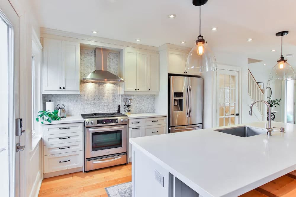 Modern kitchen with stainless steel appliances, white cabinetry, and a large island countertop.